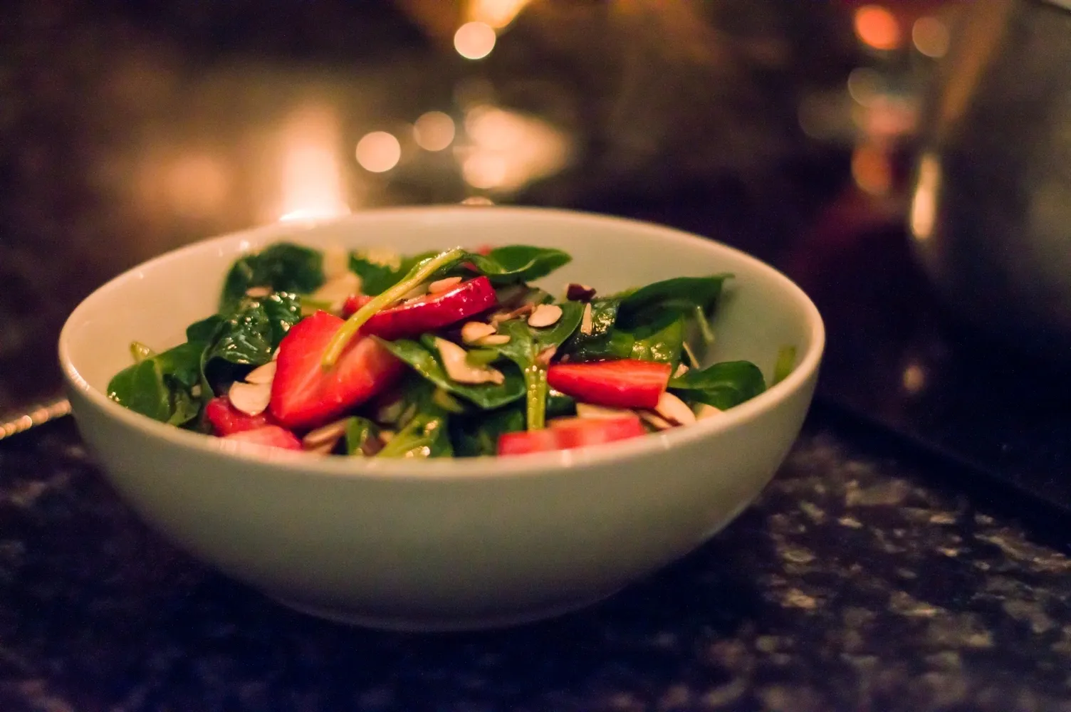 A bowl of salad with strawberries and spinach.